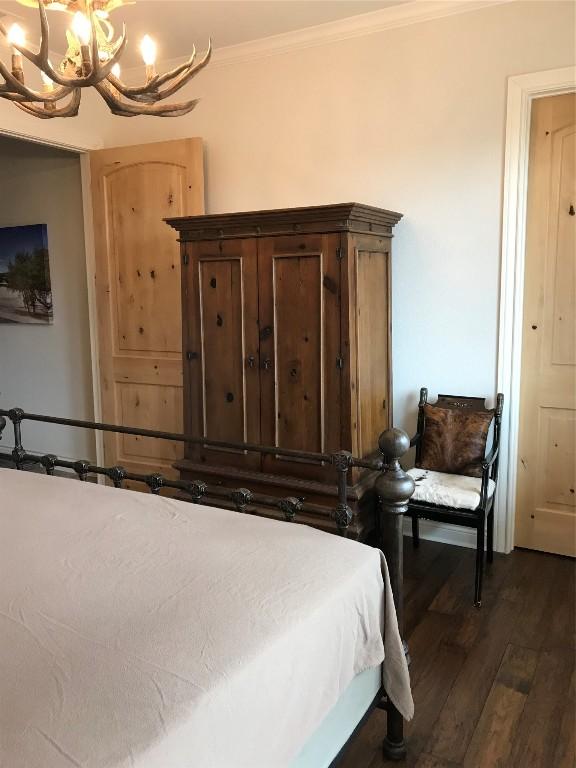 bedroom with a notable chandelier, ornamental molding, and dark hardwood / wood-style floors