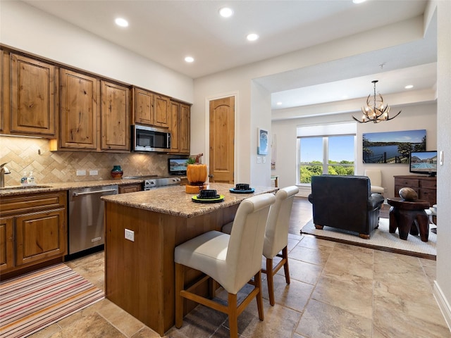 kitchen with a kitchen island, a breakfast bar, decorative backsplash, hanging light fixtures, and stainless steel appliances