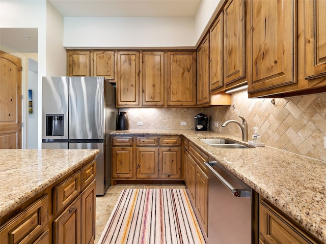 kitchen featuring tasteful backsplash, light stone countertops, appliances with stainless steel finishes, and sink