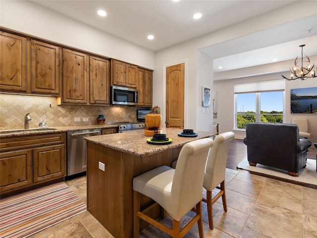 kitchen featuring pendant lighting, sink, a kitchen island, stainless steel appliances, and a kitchen bar