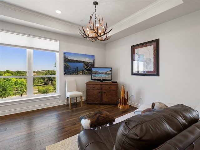 living room with a raised ceiling, crown molding, a chandelier, and dark hardwood / wood-style flooring