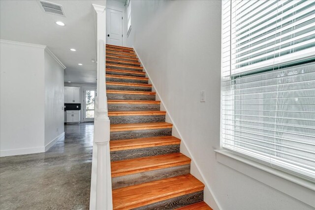 staircase featuring crown molding and concrete floors