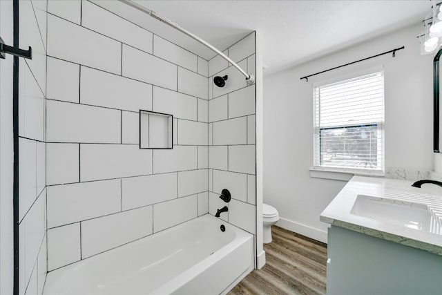 full bathroom featuring tiled shower / bath combo, vanity, wood-type flooring, and toilet