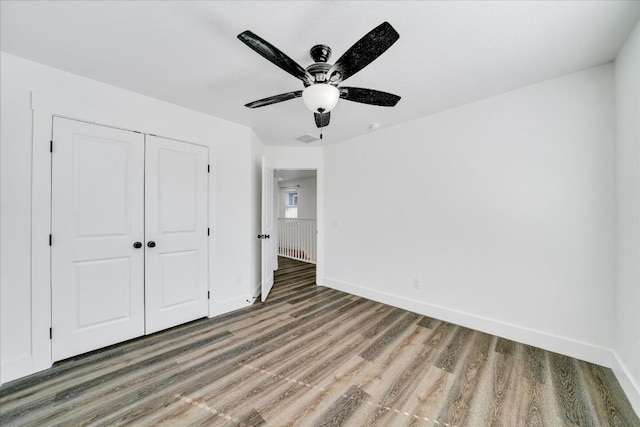 unfurnished bedroom with wood-type flooring, ceiling fan, and a closet