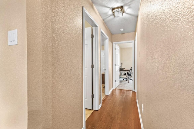 hall featuring a textured ceiling and light wood-type flooring