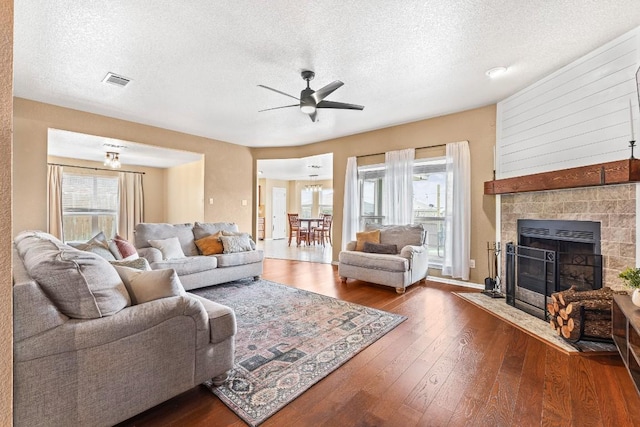 living room featuring ceiling fan, dark wood-type flooring, a fireplace, and a textured ceiling