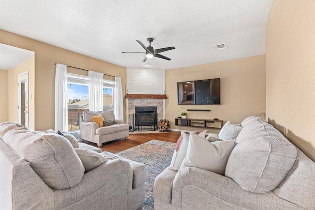 living room with hardwood / wood-style flooring, a fireplace, a textured ceiling, and ceiling fan