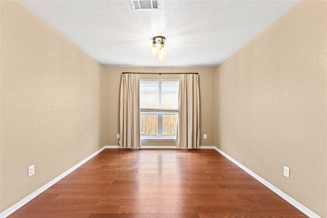 unfurnished room with hardwood / wood-style floors and a textured ceiling