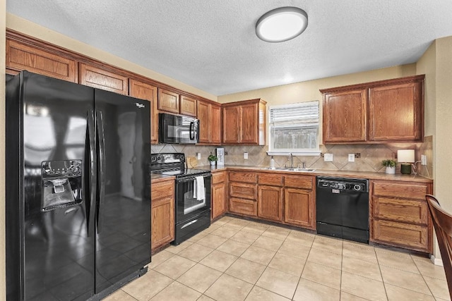 kitchen featuring tasteful backsplash, light tile patterned flooring, sink, and black appliances