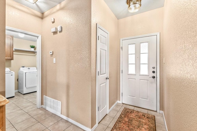 foyer entrance with washer and dryer and light tile patterned floors