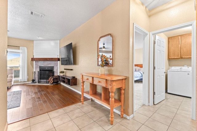 interior space featuring light tile patterned floors, washer / dryer, and a textured ceiling