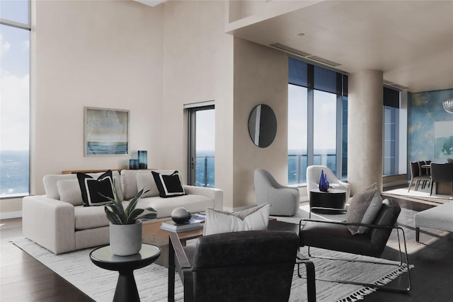 living room featuring a high ceiling, a water view, a healthy amount of sunlight, and hardwood / wood-style floors