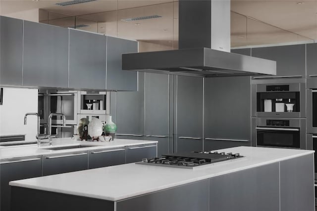 kitchen with gray cabinetry, island range hood, a center island, and gas stovetop