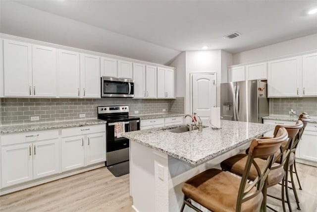 kitchen featuring white cabinetry, appliances with stainless steel finishes, and a kitchen island with sink