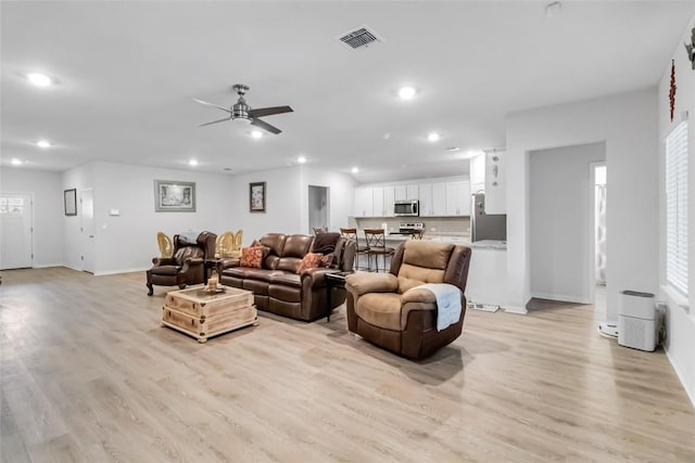 living room featuring a healthy amount of sunlight, ceiling fan, and light wood-type flooring