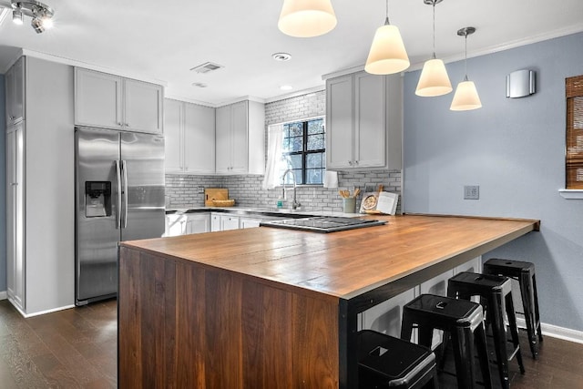 kitchen featuring stainless steel fridge, kitchen peninsula, butcher block countertops, and decorative light fixtures