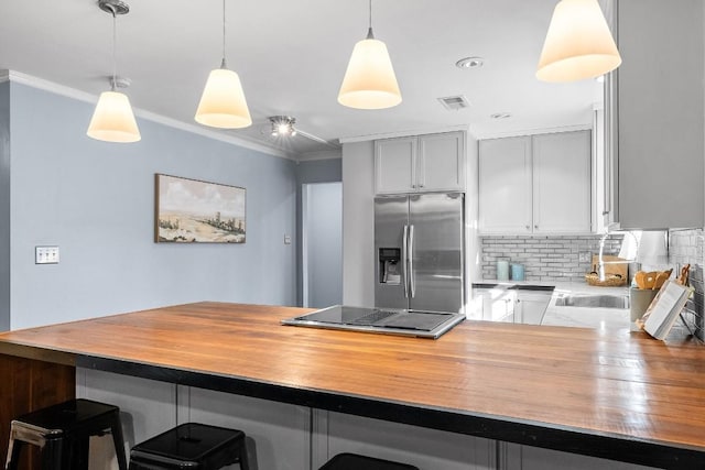 kitchen with a kitchen bar, crown molding, decorative light fixtures, stainless steel fridge with ice dispenser, and kitchen peninsula