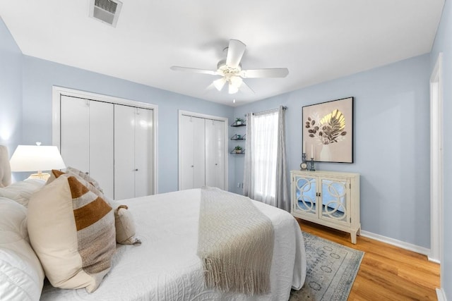 bedroom featuring two closets, ceiling fan, and light wood-type flooring