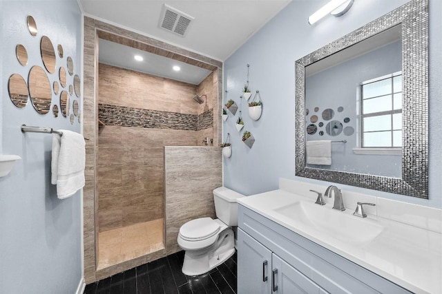 bathroom with vanity, tiled shower, and toilet