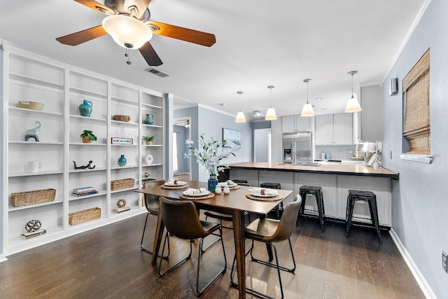 dining space with dark wood-type flooring, ceiling fan, ornamental molding, and built in shelves