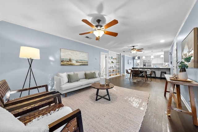 living room with crown molding, ceiling fan, and dark hardwood / wood-style floors