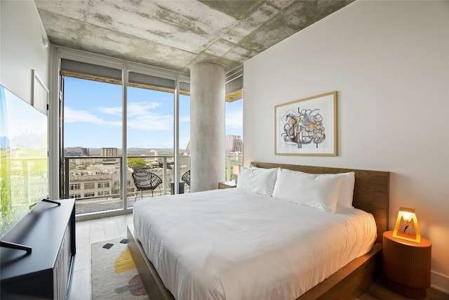 bedroom featuring a wall of windows, access to exterior, and light wood-type flooring