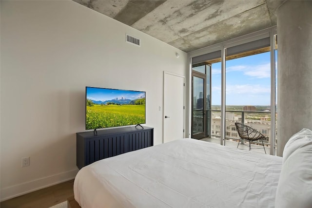 bedroom with floor to ceiling windows, wood-type flooring, and access to exterior