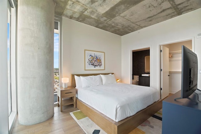 bedroom with a walk in closet, ensuite bathroom, a closet, and light wood-type flooring