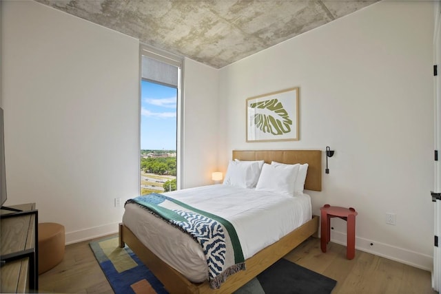 bedroom with a wall of windows and light wood-type flooring