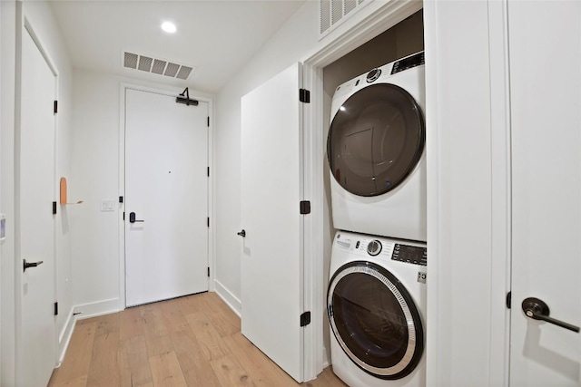 washroom featuring stacked washer and dryer and light wood-type flooring