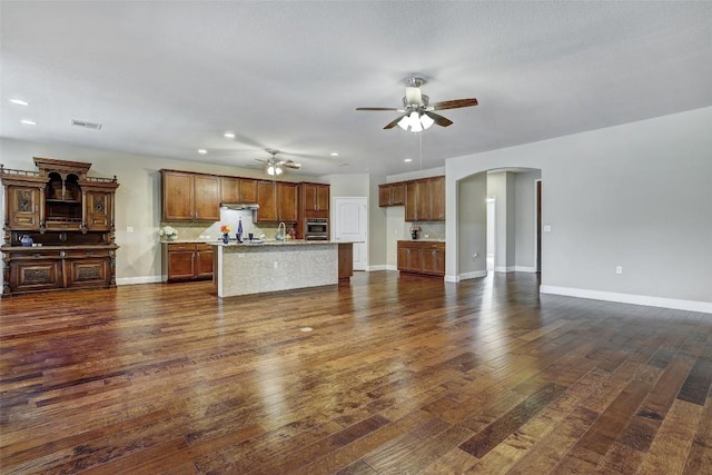 unfurnished living room featuring dark wood-type flooring and ceiling fan