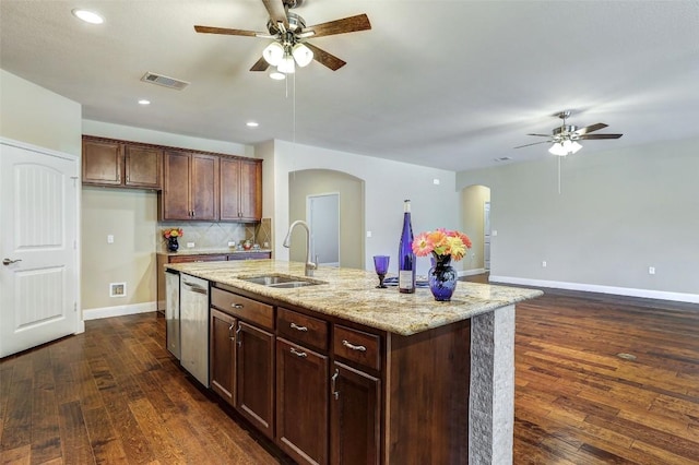 kitchen featuring dishwasher, an island with sink, sink, dark hardwood / wood-style flooring, and light stone countertops