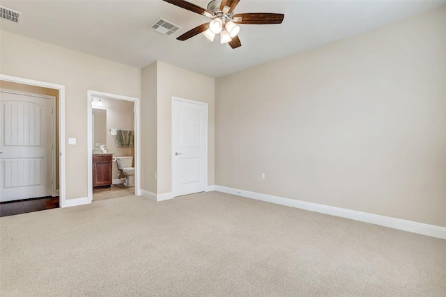 unfurnished bedroom featuring ensuite bath, light colored carpet, and ceiling fan