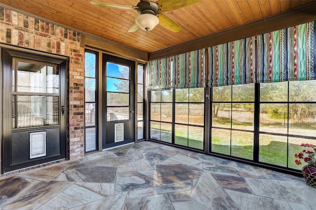 unfurnished sunroom with wood ceiling, ceiling fan, and a wealth of natural light