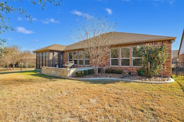 back of property with a lawn and a sunroom