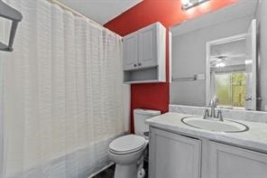 full bathroom with vanity, shower / tub combo with curtain, and toilet