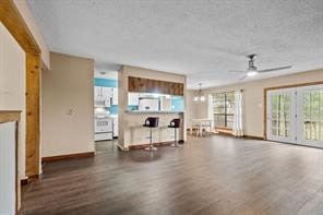 unfurnished living room featuring ceiling fan, dark wood-type flooring, and a textured ceiling