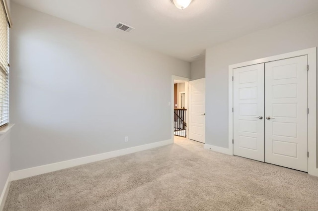 unfurnished bedroom featuring light colored carpet and a closet