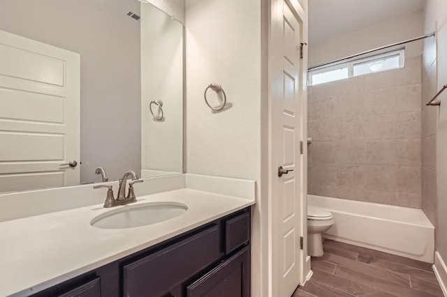 full bathroom featuring vanity, tiled shower / bath, and toilet