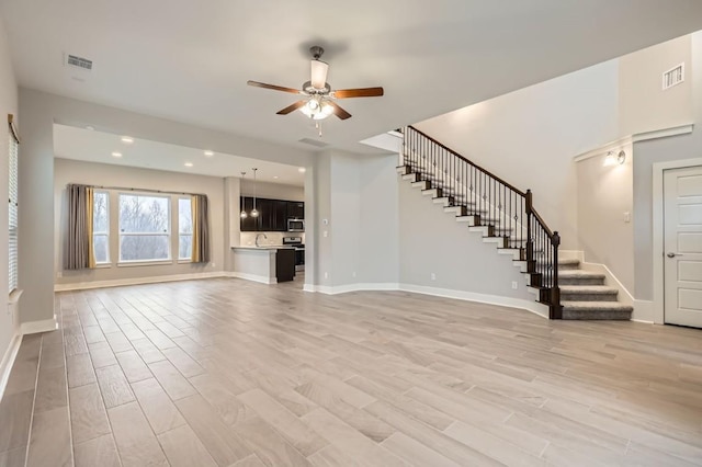 unfurnished living room featuring ceiling fan, sink, and light hardwood / wood-style floors