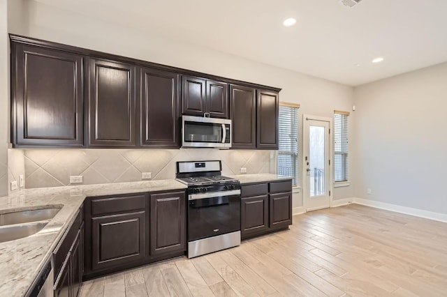 kitchen with stainless steel appliances, dark brown cabinets, light wood-type flooring, and decorative backsplash