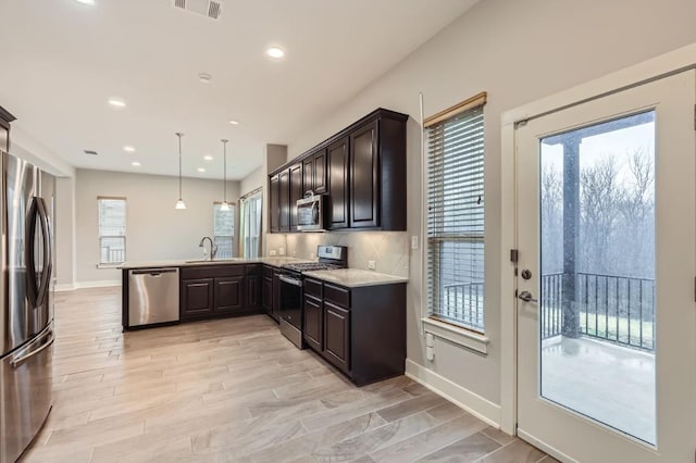 kitchen featuring dark brown cabinetry, sink, hanging light fixtures, appliances with stainless steel finishes, and kitchen peninsula