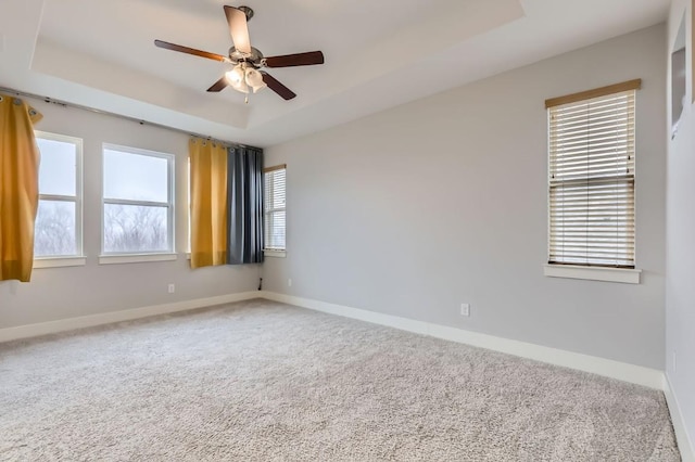 unfurnished room featuring ceiling fan, a tray ceiling, and carpet floors