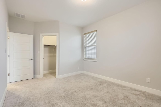 unfurnished bedroom featuring light colored carpet and a spacious closet