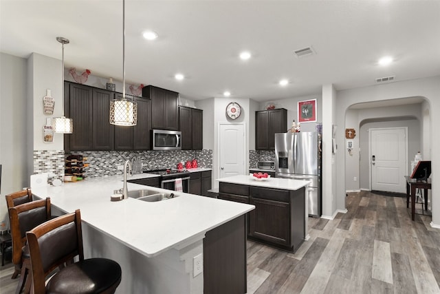 kitchen with appliances with stainless steel finishes, decorative light fixtures, sink, a kitchen breakfast bar, and kitchen peninsula