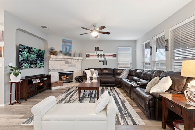 living room with ceiling fan, a fireplace, and light wood-type flooring