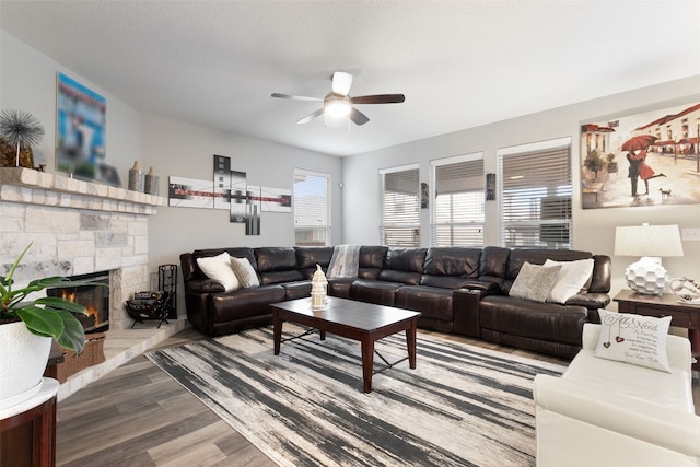 living room featuring a fireplace, a textured ceiling, wood-type flooring, and ceiling fan