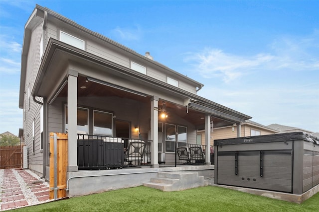 back of property with a hot tub and a porch