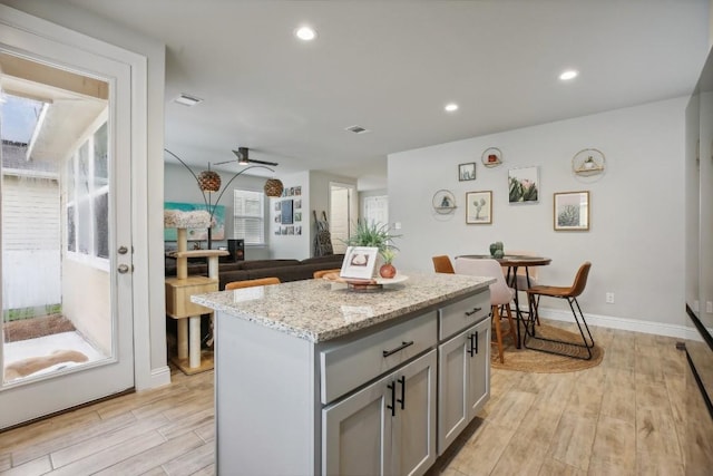 kitchen featuring a center island, gray cabinetry, ceiling fan, and light hardwood / wood-style flooring