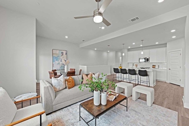 living room featuring ceiling fan and light hardwood / wood-style floors